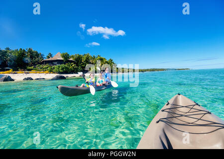 Family of mother and kids paddling on kayaks at tropical ocean water during summer vacation Stock Photo