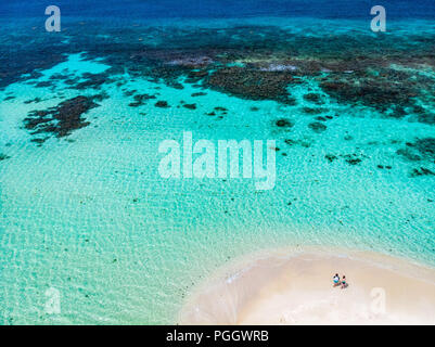 Aerial drone view of tiny tropical Mopion island sandbar, turquoise Caribbean sea and romantic couple in St Vincent and Grenadines Stock Photo