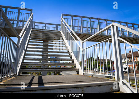 A metal stairway heading up to a footbridge crossing a busy road. Stock Photo