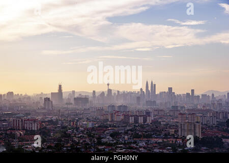 Kuala Lumpur’s iconic skyline and skyscrapers in late afternoon with golden colour and high level cirrus clouds in the blue sky Stock Photo