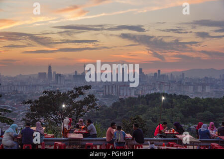 Iconic skyline of Kuala Lumpur at sunset with couples and friends enjoying the view and socialising in the foreground, Malaysia, circa September, 2017