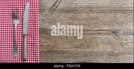 Cutlery and red checkered picnic tablecloth on wooden table, top view, copy space Stock Photo