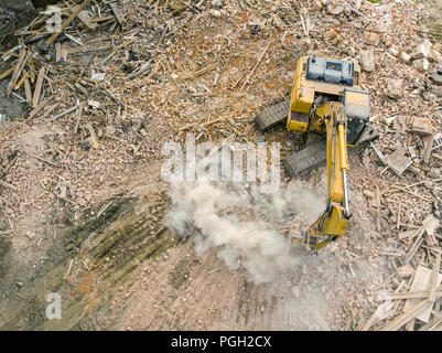 excavator backhoe clearing out urban reconstruction site. heavy industrial machinery aerial view Stock Photo