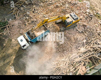 crawler excavator loading debris of a destroyed building in truck. aerial view of demolition site Stock Photo