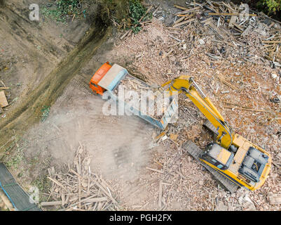 excavator loading dumper truck with debris of destroyed building. aerial photo Stock Photo
