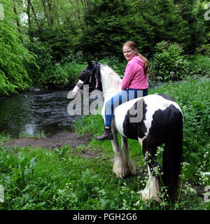 Young girl on piebald horse by the Six Mile Water, Ballyclare, County Antrim, Northern Ireland. Stock Photo