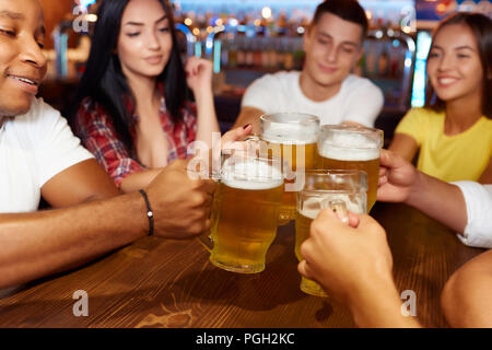 Happy multiracial friends toasting beer glasses at brewery pub Stock Photo  by engy91