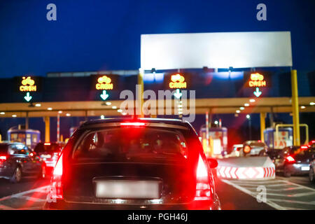 Rear view of car waiting in the line with empty white panel on the highway toll booth with cash signs at sunset. Stock Photo