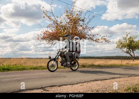 Trüstedt, Germany - August, 25, 2018: Two young people drive a Simson moped near the village of Trüstedt in Altmark, Germany. Stock Photo