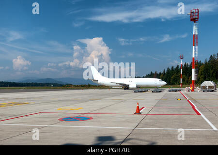 White Cargo Jet on Airport with clouds and blue sky in background, red and white airport towers and large apron, copyspace Stock Photo