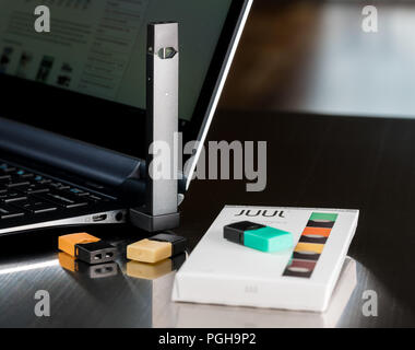Juul nicotine vapor dispenser charging in USB charger Stock Photo