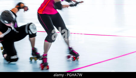Roller derby skaters close up action pan motion blur shot. One skater falls on knee. Stock Photo