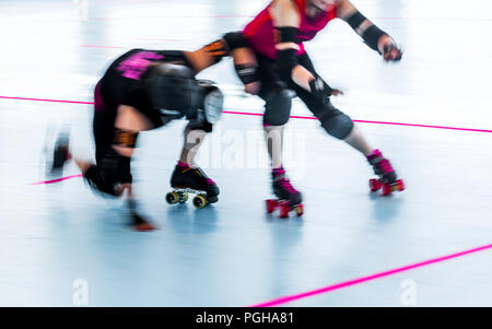 Roller derby skaters close up with motion blur. Skaters collide, one falls. Team competition. Women Stock Photo