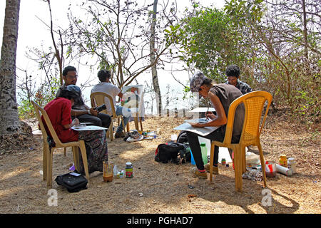 Young male and female artists create paintings at a picturesque beach side park near Siridao Beach in Goa, India Stock Photo