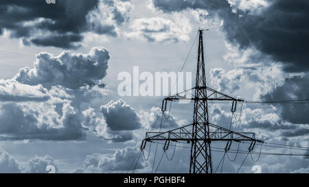 Electricity pylon top. Cloudy sky background. Power tower detail. Wres of electric transmission system. Dramatic blue cloudscape, dark ominous clouds. Stock Photo