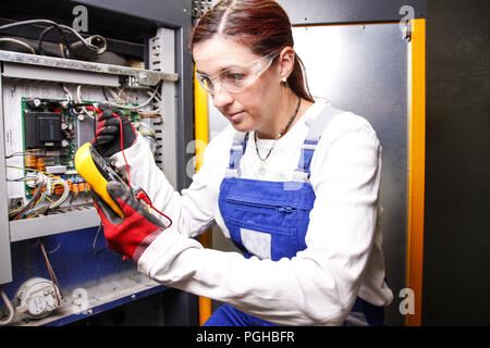 female electrician fixing an engine control panel Stock Photo