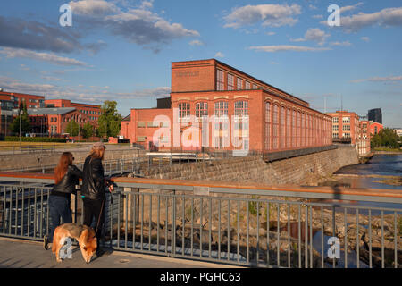 Tampere, Finland - June 10, 2018: People admire the view from the dam on Tammerkoski, the channel of rapids in Tampere. There are four power stations  Stock Photo