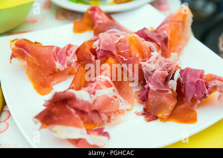 Prosciutto with melon - exquisite Italian appetizer in white plate on the table Stock Photo