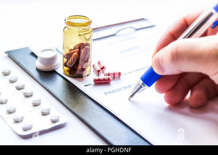 Bottle with pills and doctor writing prescription receipt Stock Photo