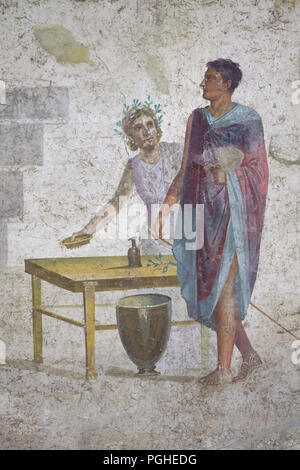 Jason depicted in the Roman fresco from the House of Jason (Casa di Giasone) in Pompeii (20-25 AD), now on display in the National Archaeological Museum (Museo Archeologico Nazionale di Napoli) in Naples, Campania, Italy. Jason recognisable by his missing sandal depicted next to the servant places the items required in the sacrificial ritual on a trapeza (Roman low table). Stock Photo
