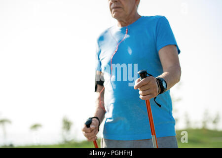 Mid section portrait of active senior man practicing Nordic walking with poles outdoors in park, copy space Stock Photo