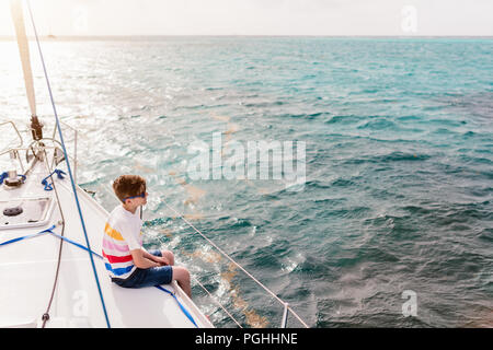 Teenage boy enjoying sailing on board a chartered catamaran or yacht Stock Photo