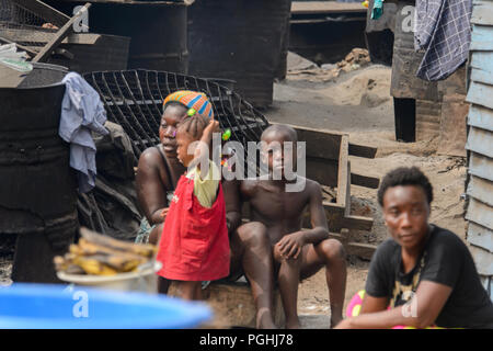 ACCRA, GHANA - Jan 8, 2017: Unidentified Ghanaian woman with her children sit at the local market. People of Ghana suffer of poverty due to the econom Stock Photo