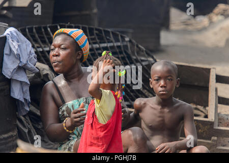 ACCRA, GHANA - Jan 8, 2017: Unidentified Ghanaian woman with her children sit at the local market. People of Ghana suffer of poverty due to the econom Stock Photo