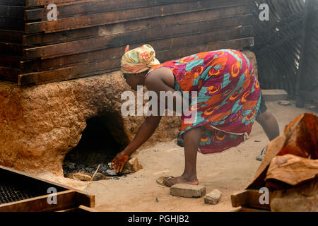 ACCRA, GHANA - Jan 8, 2017: Unidentified Ghanaian woman bends down to the fireplace at the local market. People of Ghana suffer of poverty due to the  Stock Photo