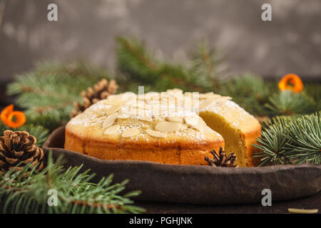 Traditional Christmas (Norwegian) almond cake in Christmas decorations, dark background. Christmas dessert concept. Stock Photo