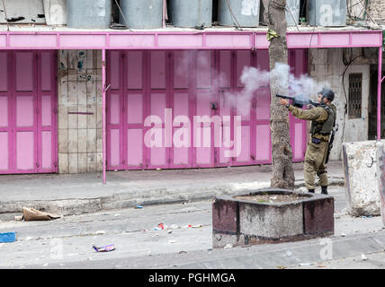 Hebron, Palestine, November 29, 2013: Israel Defence Forces soldier is shooting a gas grenade to disperse Palestinian young man during riots in Hebron Stock Photo