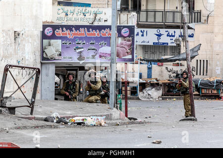 Hebron, Palestine, November 29, 2013:  Israel Defence Forces soldiers are moving forward through the streets pushing off Palestinians during riots in  Stock Photo