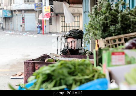 Hebron, Palestine, November 29, 2013:  Israel Defence Forces sniper is pointing an assault gun at Palestinians during riots in Hebron’s old town. Stock Photo