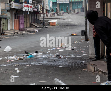 Hebron, Palestine, November 29, 2013:   Young Palestinians leans out to check Israeli soldiers’ position during riots in Hebron’s old town. Stock Photo