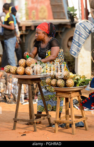OUIDAH, BENIN - Jan 10, 2017: Unidentified Beninese sells pineapples at the local market. Benin people suffer of poverty due to the bad economy Stock Photo