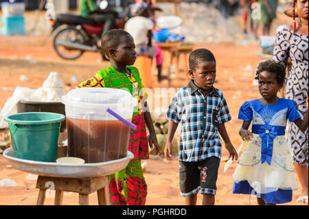 OUIDAH, BENIN - Jan 10, 2017: Unidentified Beninese children walk at the local market. Benin children suffer of poverty due to the bad economy Stock Photo