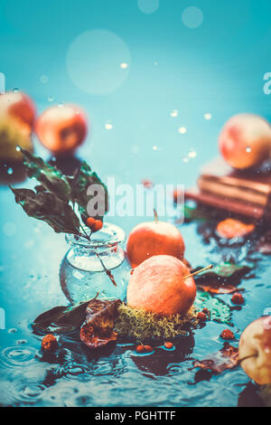 Autumn apples under rain still life. Fall harvest header with water drops and copy space. Red small ranet apples and fallen leaves. Cross process effect Stock Photo