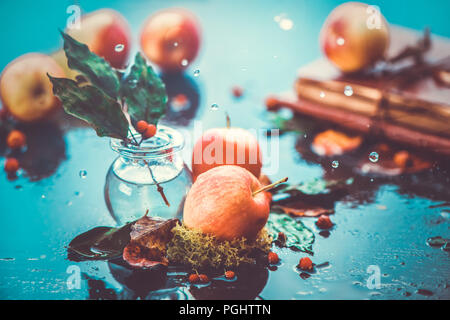 Autumn apples under rain still life. Fall harvest header with water drops and copy space. Red small ranet apples and fallen leaves. Cross process effect Stock Photo