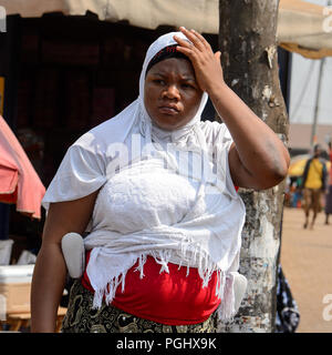 CENTRAL REGION, GHANA - Jan 17, 2017: Unidentified Ghanaian woman in white headscarf touches her head in local village. People of Ghana suffer of pove Stock Photo