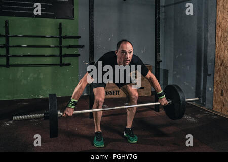 Young man at a crossfit gym lifting a barbell. Stock Photo