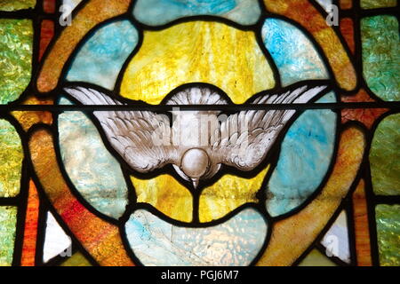 Antique christian stained glass window depicting the Holy Spirit as a dove in flight. Stock Photo