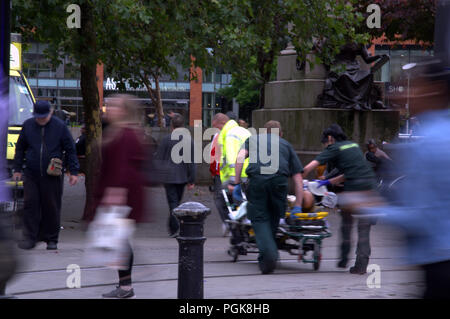 Manchester, UK. 27 August, 2018  Paramedics in central Manchester rush a patient to an ambulance.  GMB union paramedics in north-west England have stopped their weekly strikes so that their union can discuss pay issues with the managers of the North West Ambulance Service. For seven weeks the paramedics have carried out 26 hour walkouts at weekends. Credit Terry Waller/Alamy Live News Stock Photo