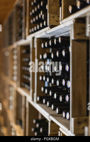close up of resting wine bottles stacked on wooden racks in cellar Stock Photo
