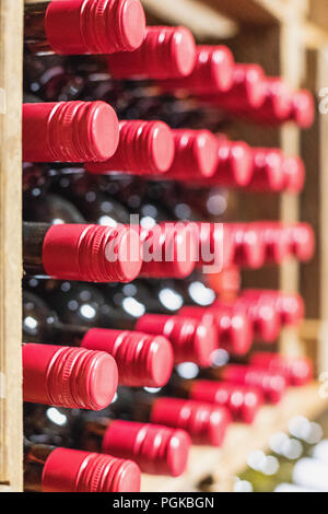 close up of resting wine bottles stacked on wooden racks in cellar Stock Photo