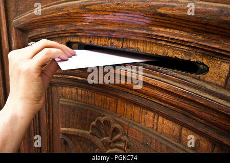 woman hand putting an envelope into a mail slot Stock Photo