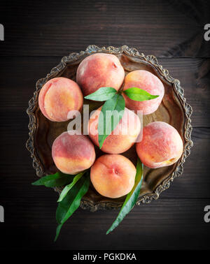 fresh ripe peaches in a round iron plate, top view Stock Photo