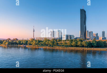 Beautiful cityscape with modern buildings, the tallest skyscraper in Austria and the blue Danube river, in the Donau district of Vienna, at sunset. Stock Photo