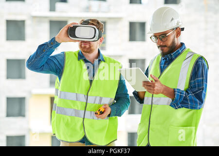 Waist up portrait of two contemporary workers using VR to visualize projects on construction site Stock Photo