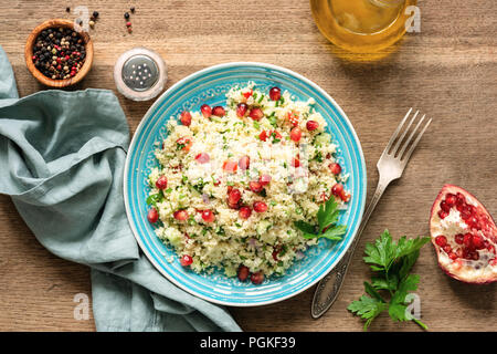Couscous salad Tabbouleh with pomegranate seeds served on traditional turquoise plate. Arabic food Stock Photo
