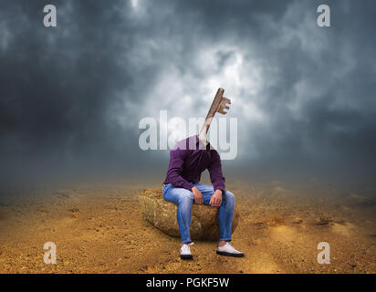 Man with key secret path instead of a head sitting on the stone, desert storm on background Stock Photo